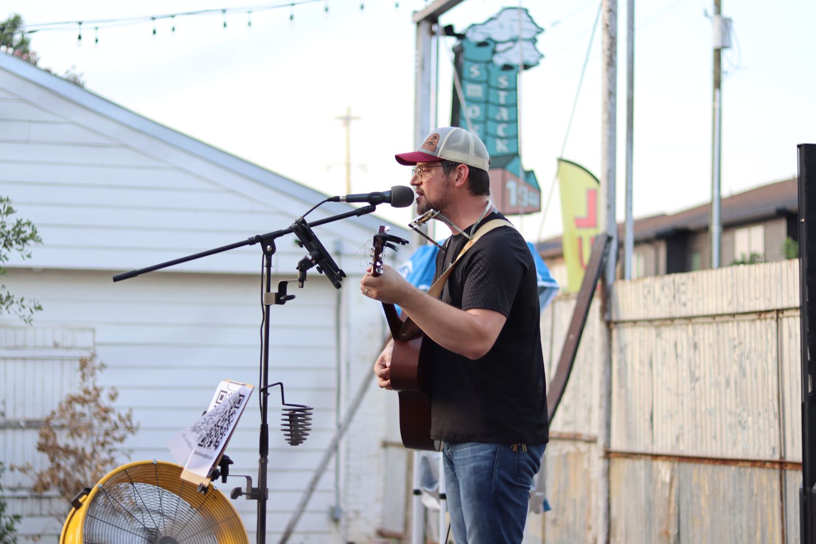 Wilhyme singing outdoors with an acoustic guitar